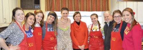 Chi Omega group photo in baking aprons with Dr. and Mrs. Arnn.