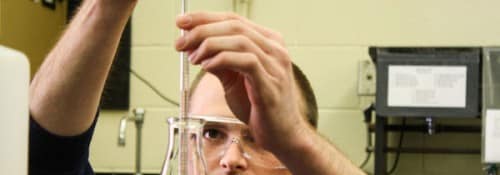 Luke Bessmer measuring out solution of pink liquid from a chemistry flask.