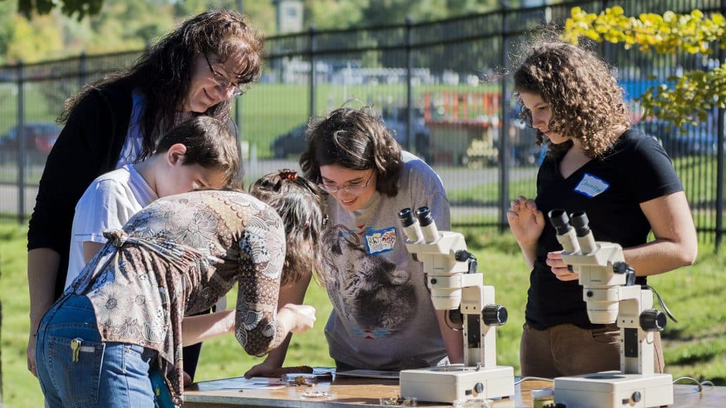 Arboretum visitors examining some of the plant life with microscopes.
