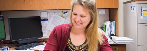 Dr. Courtney Meyet examines student research papers in her office