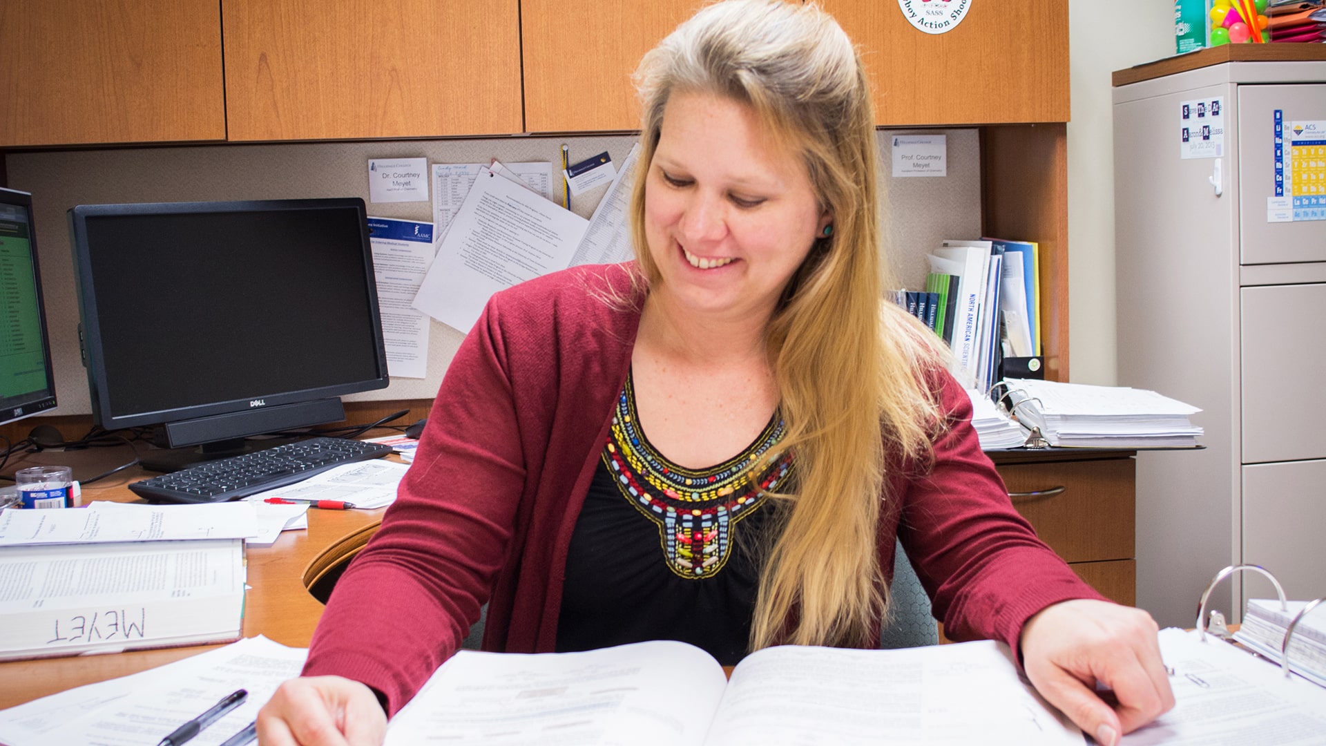 Dr. Courtney Meyet examines student research papers in her office