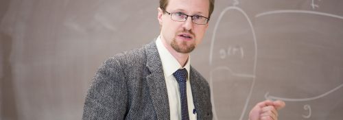 Dr. Gaebler in front of a blackboard, teaching class.