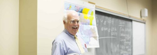Tom Conner teaching a class, book in hand.