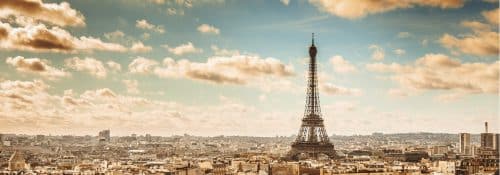 Aerial view of Paris, France showing the Eiffel Tower against the clouds.