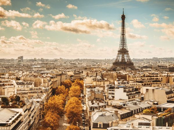 Aerial view of Paris, France showing the Eiffel Tower against the clouds.