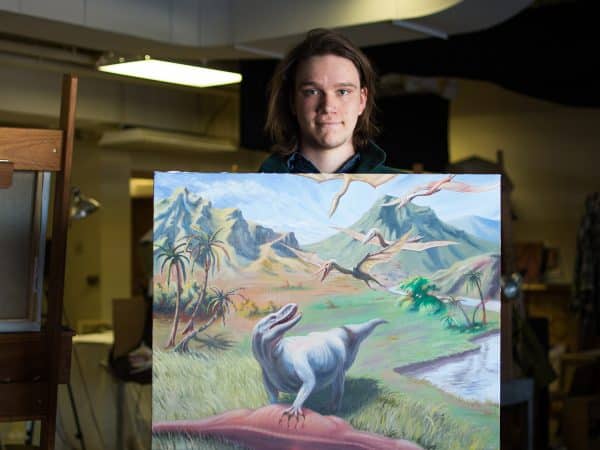 Forester McClatchey with his own artwork conceptualizing dinosaurs.