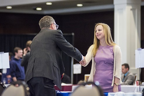 People talking at booths during a Classical School job fair.