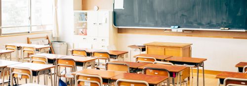 Elementary school classroom with chalkboard and desks.