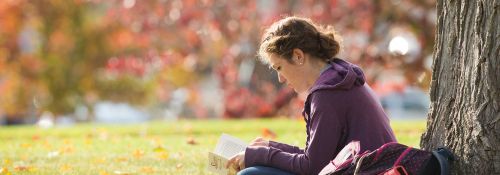 Student reading book outside on campus