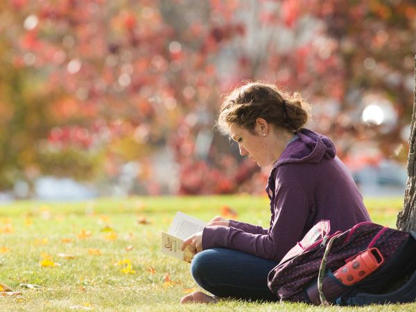 Student reading book outside on campus