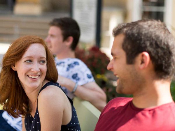 Several students laughing on a bench.