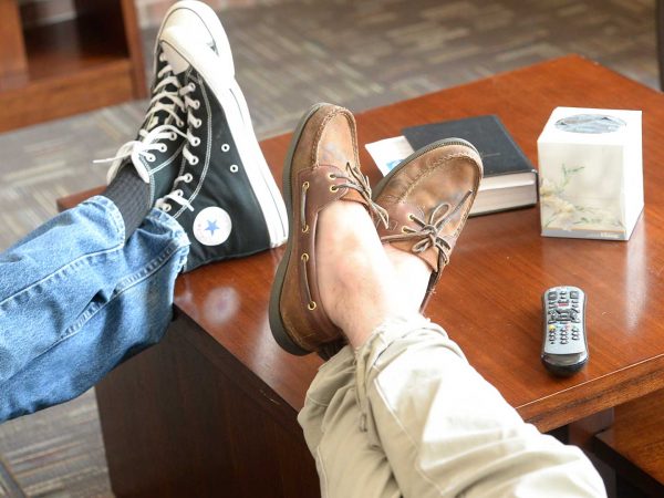 A couple resting their feet on a coffee table, relaxing.