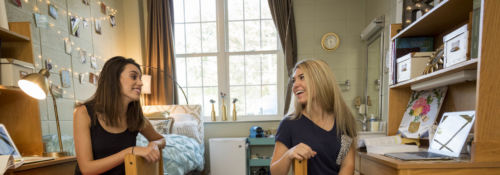 Two women conversing in their dorm room.
