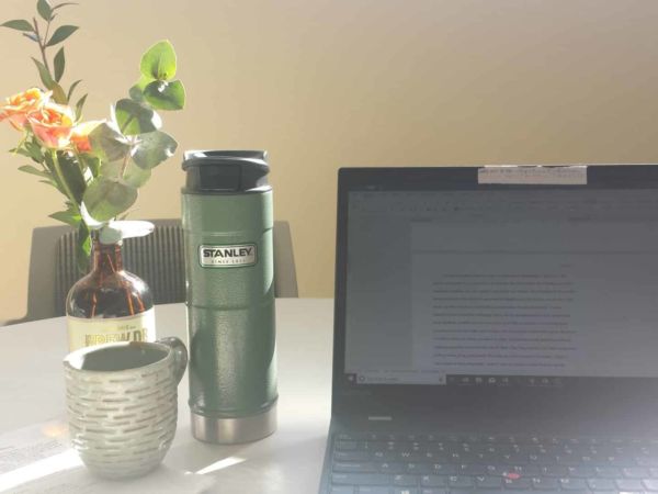 Thermos of tea and a laptop open for editing essays.