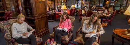 Three students studying in the Heritage room of the Hillsdale College Library..