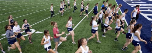Hillsdale Track team running on the football field during practice.