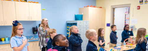young students saluting the flag academy