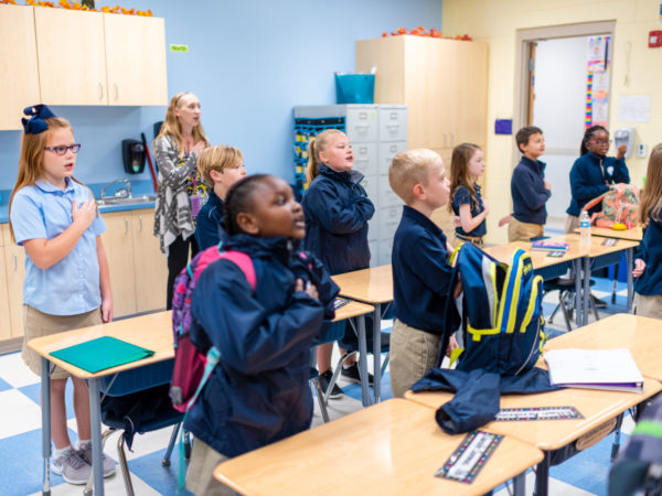 young students saluting the flag academy
