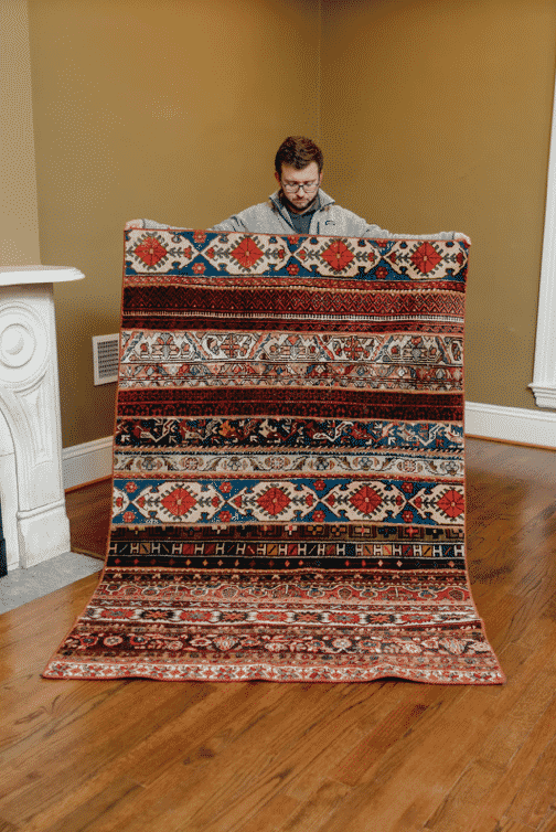 Evan Gage holding large rug