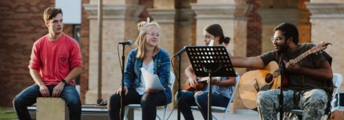 Two male and two female students performing music at an outdoor concert