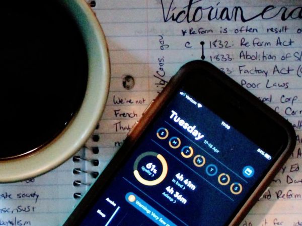 Photo of a coffee cup and phone with sleep app open, sitting on a page of student's notes