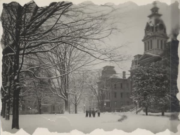 An old photograph of Central Hall in the snow with students standing nearby