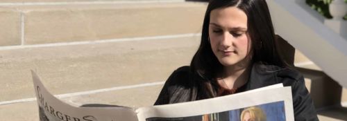 Students sits on Central Hall front steps, reading The Collegian