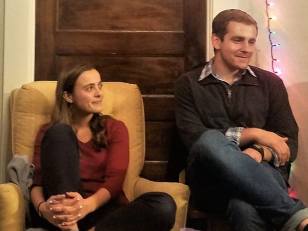 Three college students sit in separate chairs in a living room