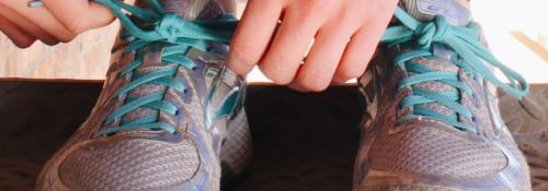 running shoes with two hands tying one shoe