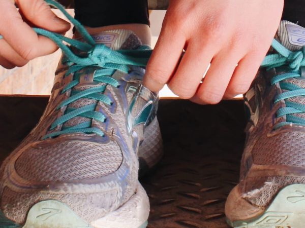 running shoes with two hands tying one shoe