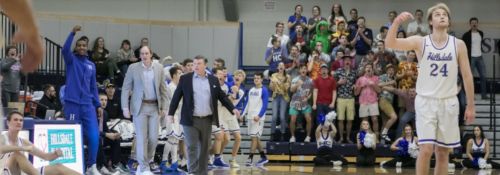 Basketball players, coaches, and student section at a basketball game