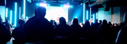 shadows of people at a concert with blue lazers