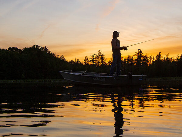A fisherman silhouetted by sunset.