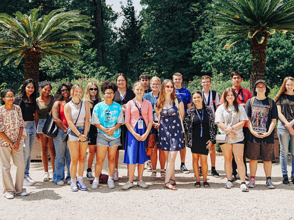 A group of students pose for a group photo on a beach.